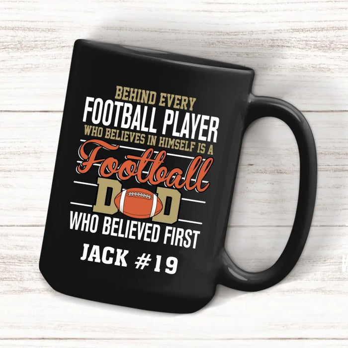 Personalized Behind Every Football Player Who Believes In Himself Is A Football Dad Who Believe First Mug, Custom Mug For Football Dad, Football Mom