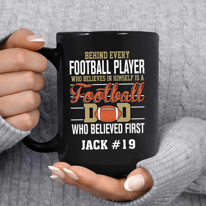 Personalized Behind Every Football Player Who Believes In Himself Is A Football Dad Who Believe First Mug, Custom Mug For Football Dad, Football Mom